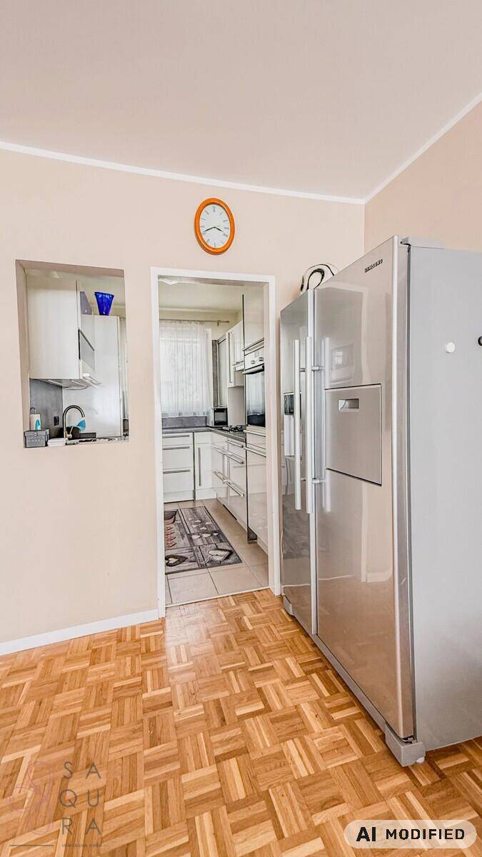 Flur mit großem Kühlschrank und Durchgang zur Küche, mit Parkettboden.