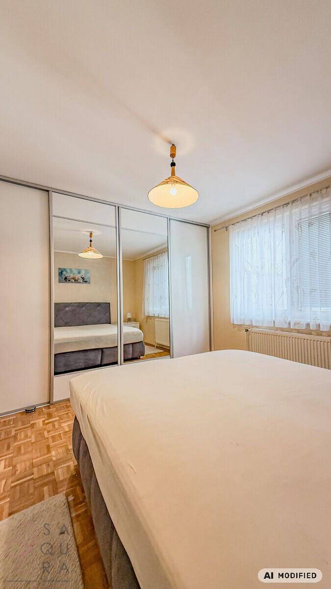 Schlafzimmer mit großem Bett und Spiegelschränken, hell durch Fenster, mit Parkettboden.