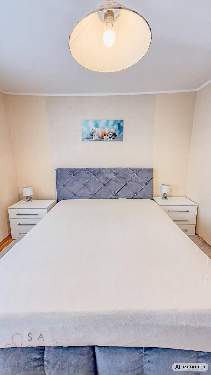 Schlafzimmer mit großem Polsterbett und Nachttischen, hell und modern eingerichtet.