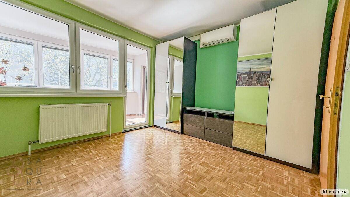 Geräumiges Zimmer mit grün gestrichenen Wänden, Parkettboden und Spiegelschränken.