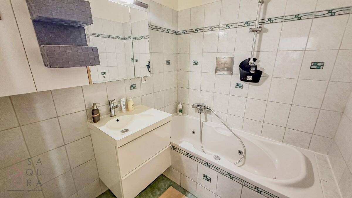 Badezimmer mit Badewanne, Waschbecken und hellen Fliesen, funktional und sauber.