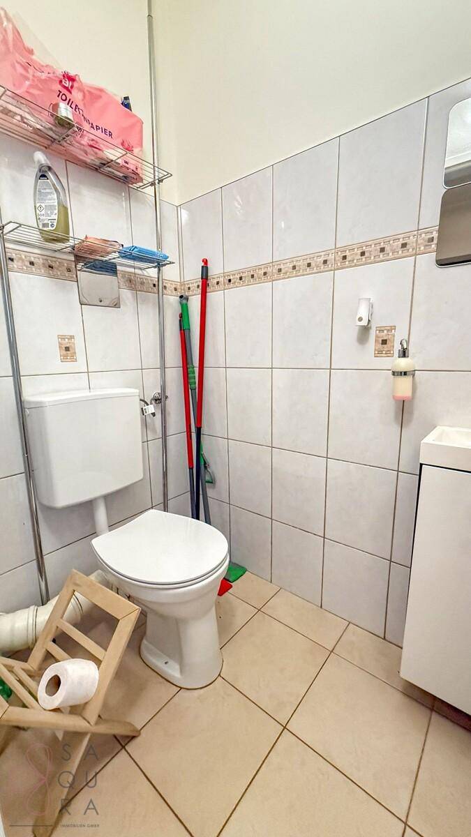 Separate Toilette mit Waschbecken und hellen Fliesen, funktional und sauber.