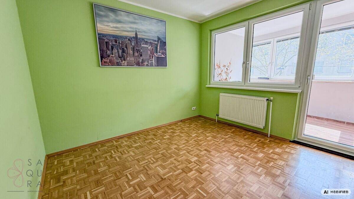 Helles Zimmer mit grün gestrichenen Wänden, Parkettboden und Zugang zum Balkon.