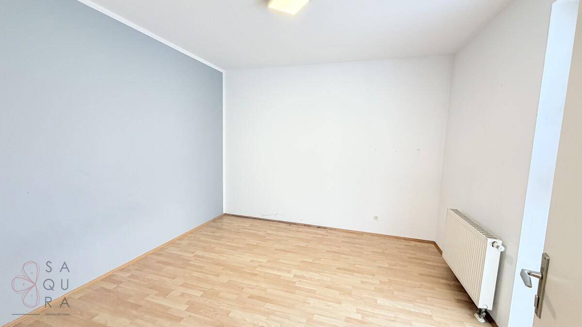 Leerer Raum mit Holzboden, weißen Wänden und einer hellblauen Akzentwand.