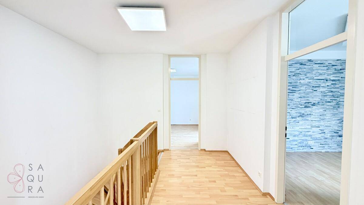 Heller Flur im Obergeschoss mit Holzboden und einer dekorativen Steinwand.
