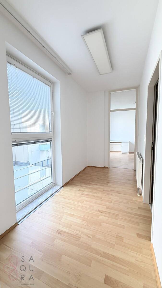 Heller Flur mit Holzboden und großem Fenster, das viel Licht in den Raum bringt.