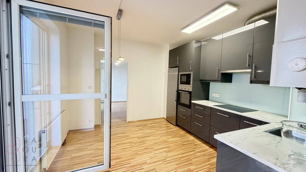 Moderne Küche mit dunkelgrauen Schränken, integrierten Geräten und hellem Holzboden.