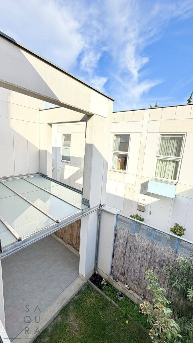 Blick von oben auf einen kleinen Gartenbereich mit Rasen und eine überdachte Terrasse.