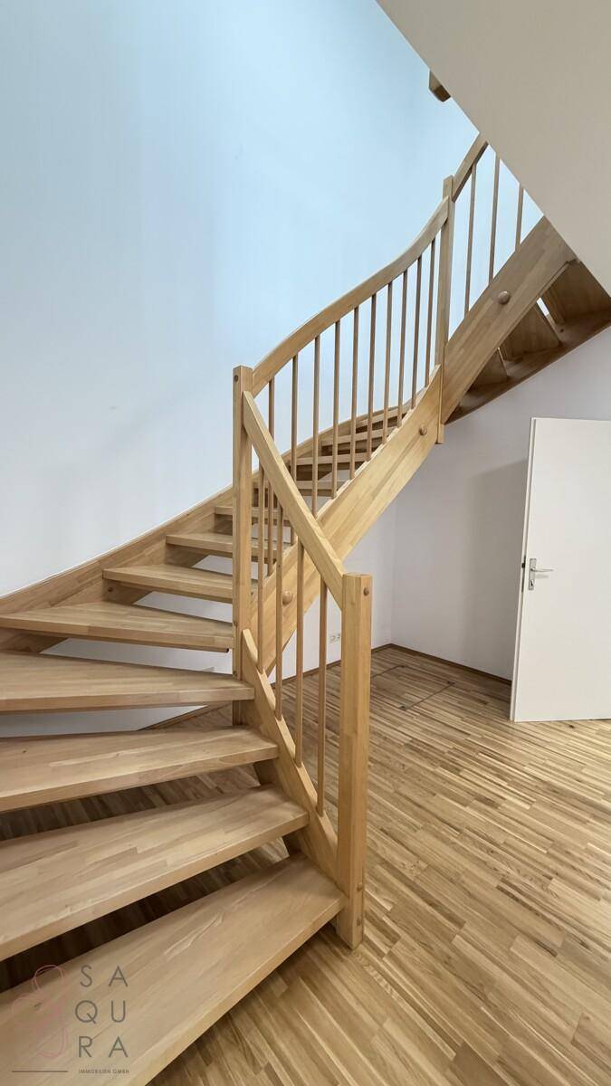 Elegante Holztreppe mit passendem Geländer, die die verschiedenen Etagen des Hauses verbindet.