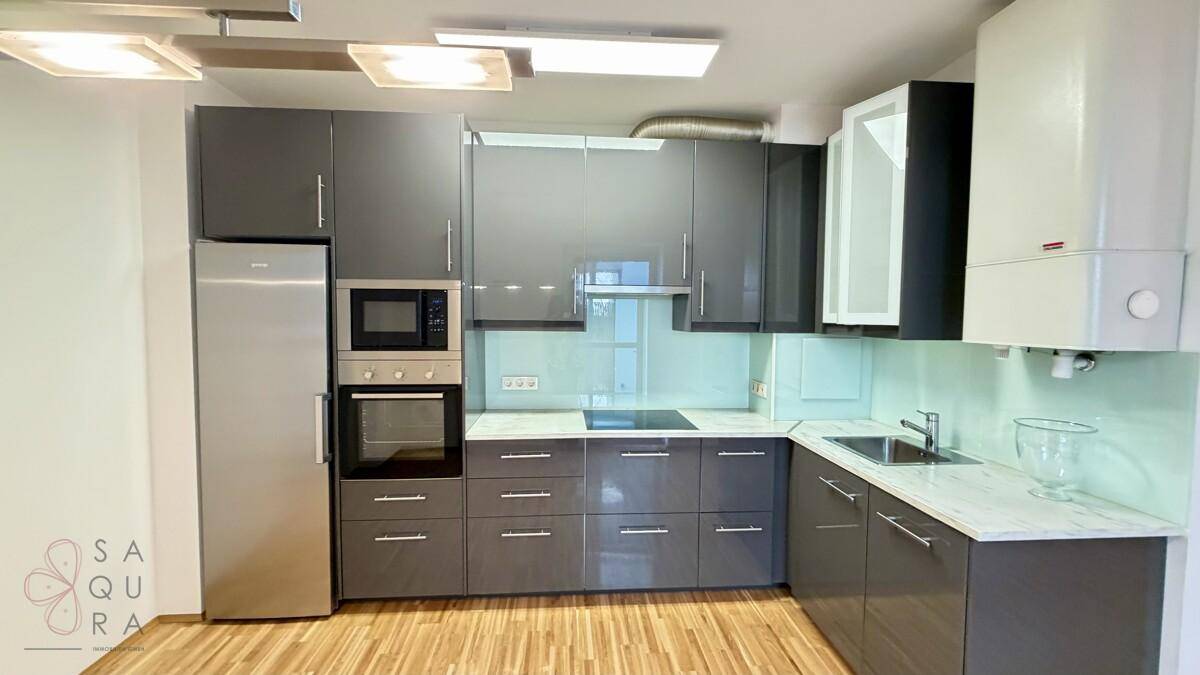 Moderne Küche mit dunkelgrauen Hochglanzschränken, integrierten Geräten und hellem Holzboden.