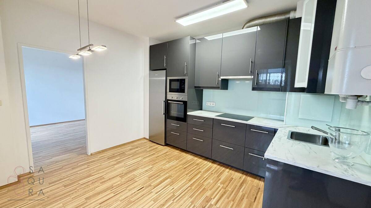Moderne Küche mit dunkelgrauen Schränken, integrierten Geräten und hellem Holzboden.