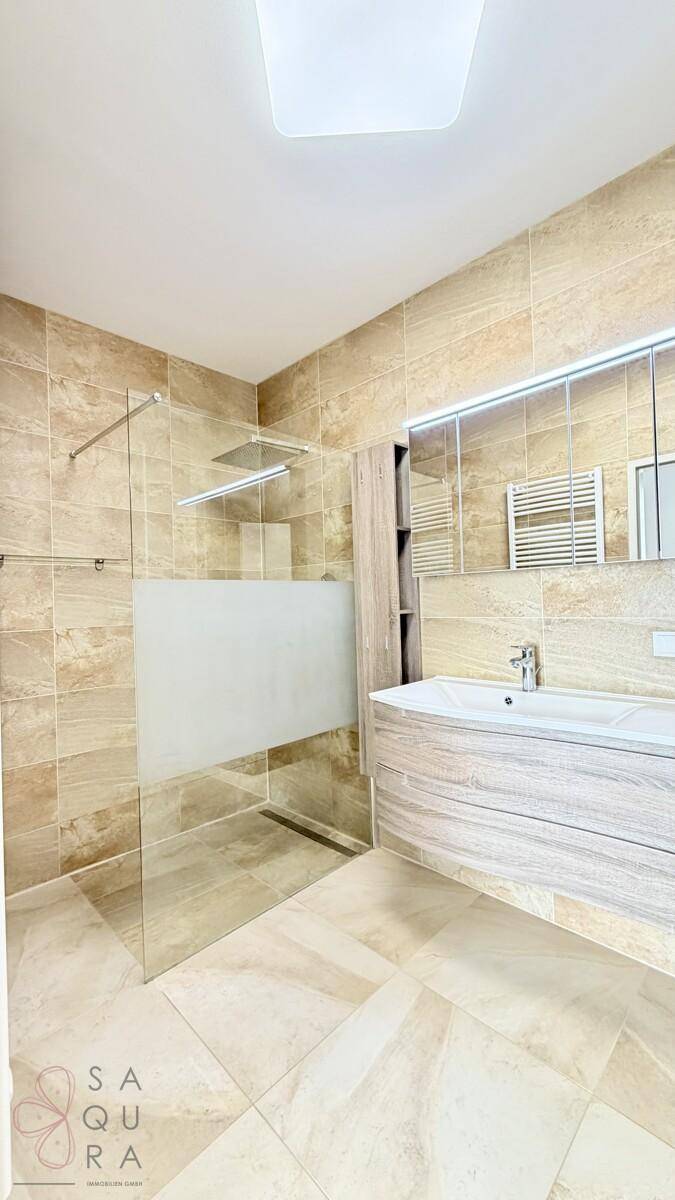 Modernes Badezimmer mit begehbarer Dusche, Waschtisch und beheiztem Handtuchhalter.