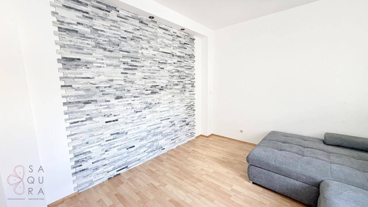 Heller Raum mit Holzboden und einer auffälligen Steinwand als dekoratives Element.