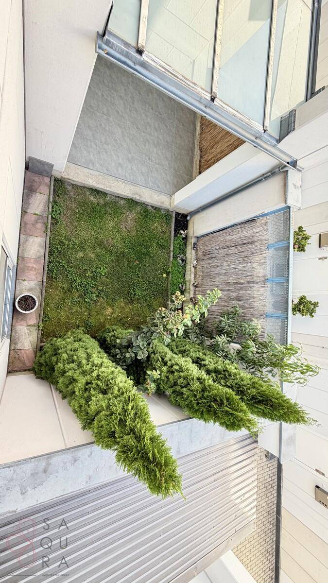 Blick von oben auf einen kleinen Gartenbereich mit Rasen und immergrünen Pflanzen.