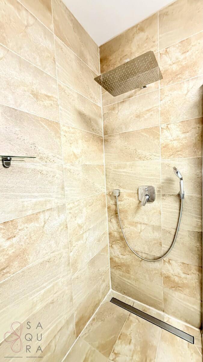 Moderne begehbare Dusche mit Regenduschkopf und Handbrause in beigefarbenen Fliesen.