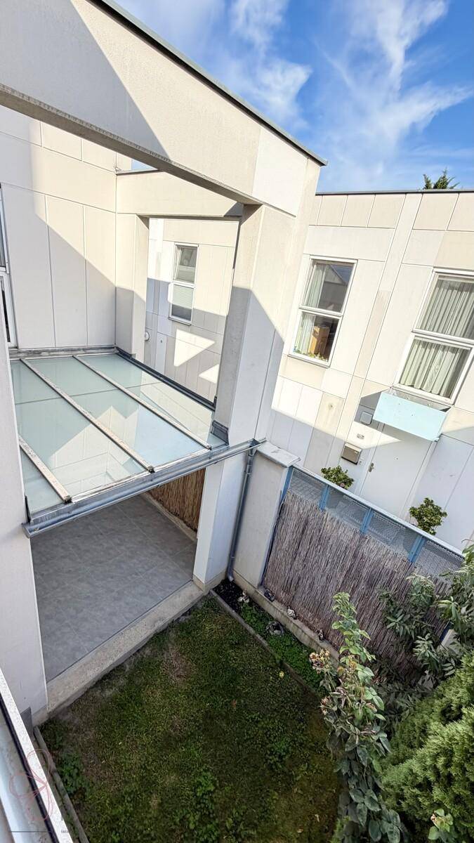 Blick von oben auf einen kleinen Gartenbereich mit Rasen und eine überdachte Terrasse.