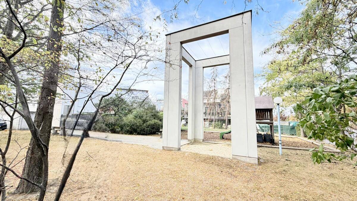 Öffentlicher Parkbereich mit moderner Architektur und einem Spielplatz im Hintergrund.