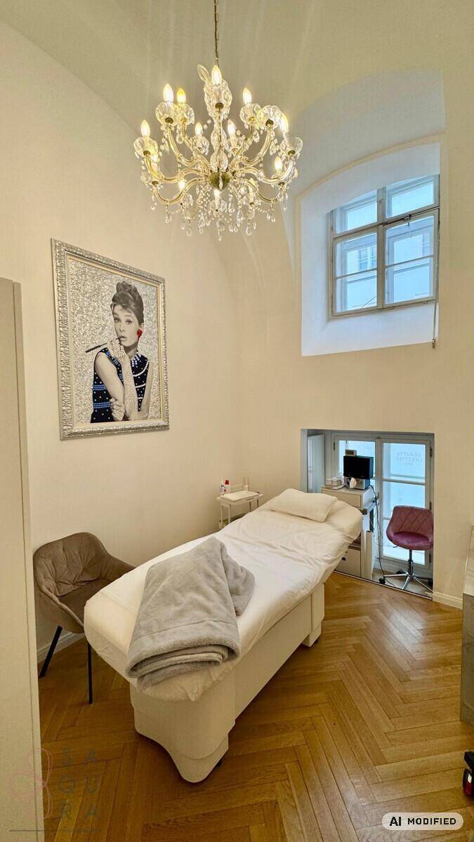 Stilvoller Behandlungsraum mit Kronleuchter, Kunstwerk und einem hohen Fenster, das viel Licht spendet.