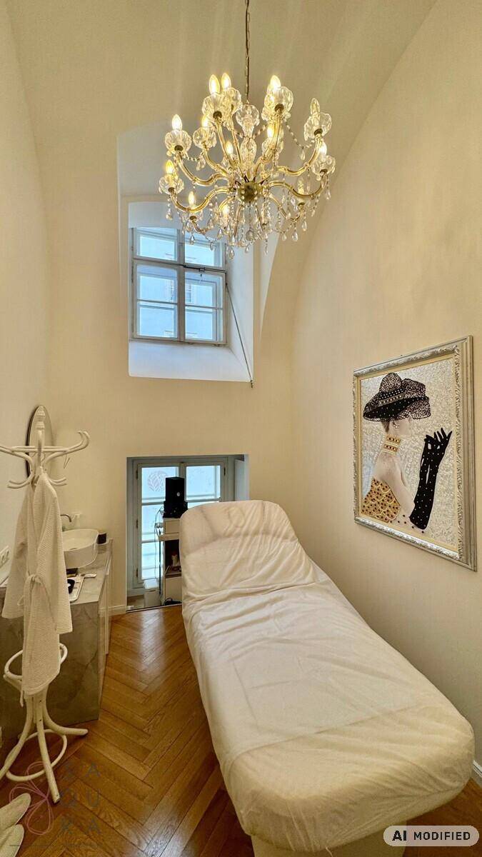 Behandlungsraum mit eleganter Einrichtung, Kronleuchter und einem hohen Fenster, das den Raum erhellt.