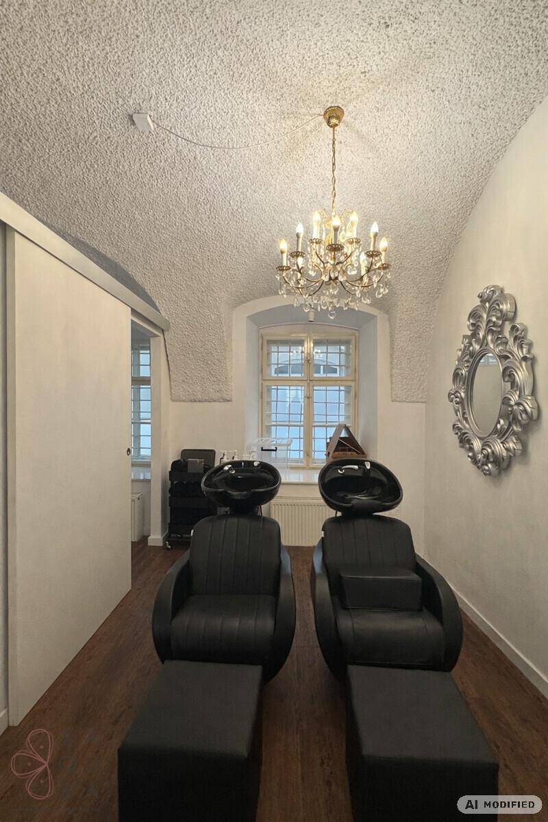 Friseursalon mit zwei Waschbecken, Kronleuchter und einem Fenster in einem Raum mit Gewölbedecke.