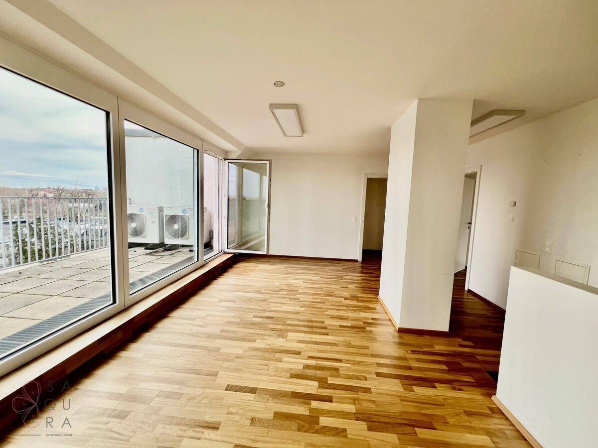 Heller Wohnraum mit Holzboden und direktem Zugang zu einer großen Dachterrasse mit Klimaanlagen-Außengeräten.