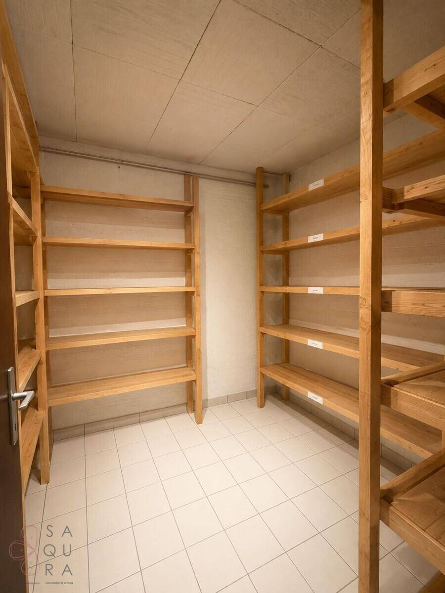 Geräumiger Abstellraum mit praktischen Holzregalen und Fliesenboden für viel Stauraum.