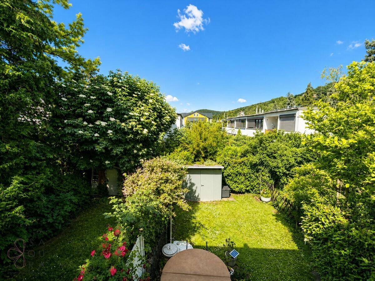 Sonniger Gartenbereich mit Whirlpool, kleinem Gartenhaus und viel Grünfläche.