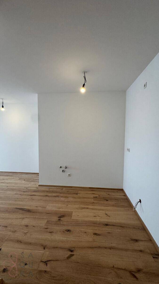 Leerer Raum mit Holzboden und weißen Wänden, vorbereitet für die weitere Gestaltung.
