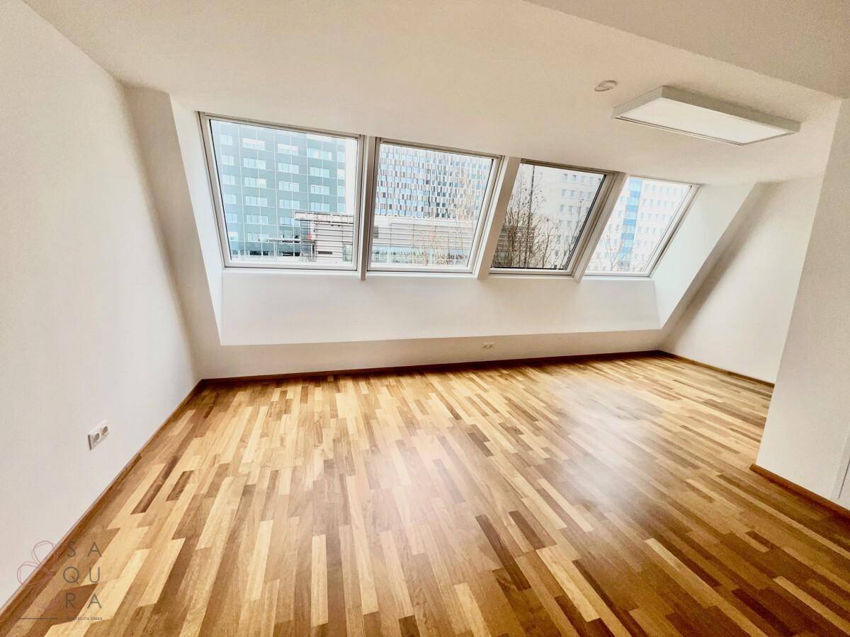 Helles Schlafzimmer mit Holzboden, Dachschrägen und großen Dachfenstern, die einen weiten Blick ermöglichen.