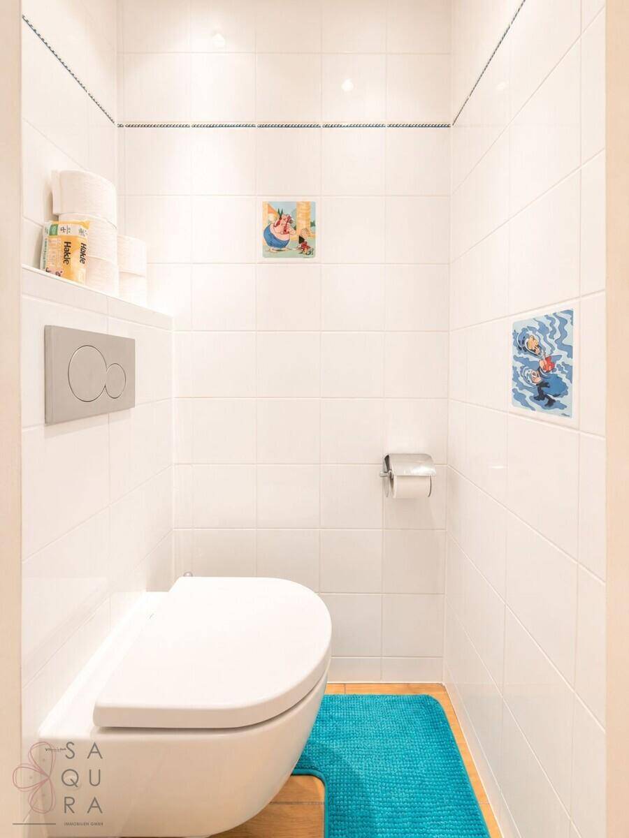 Separates WC mit weißen Fliesen und wandhängender Toilette.