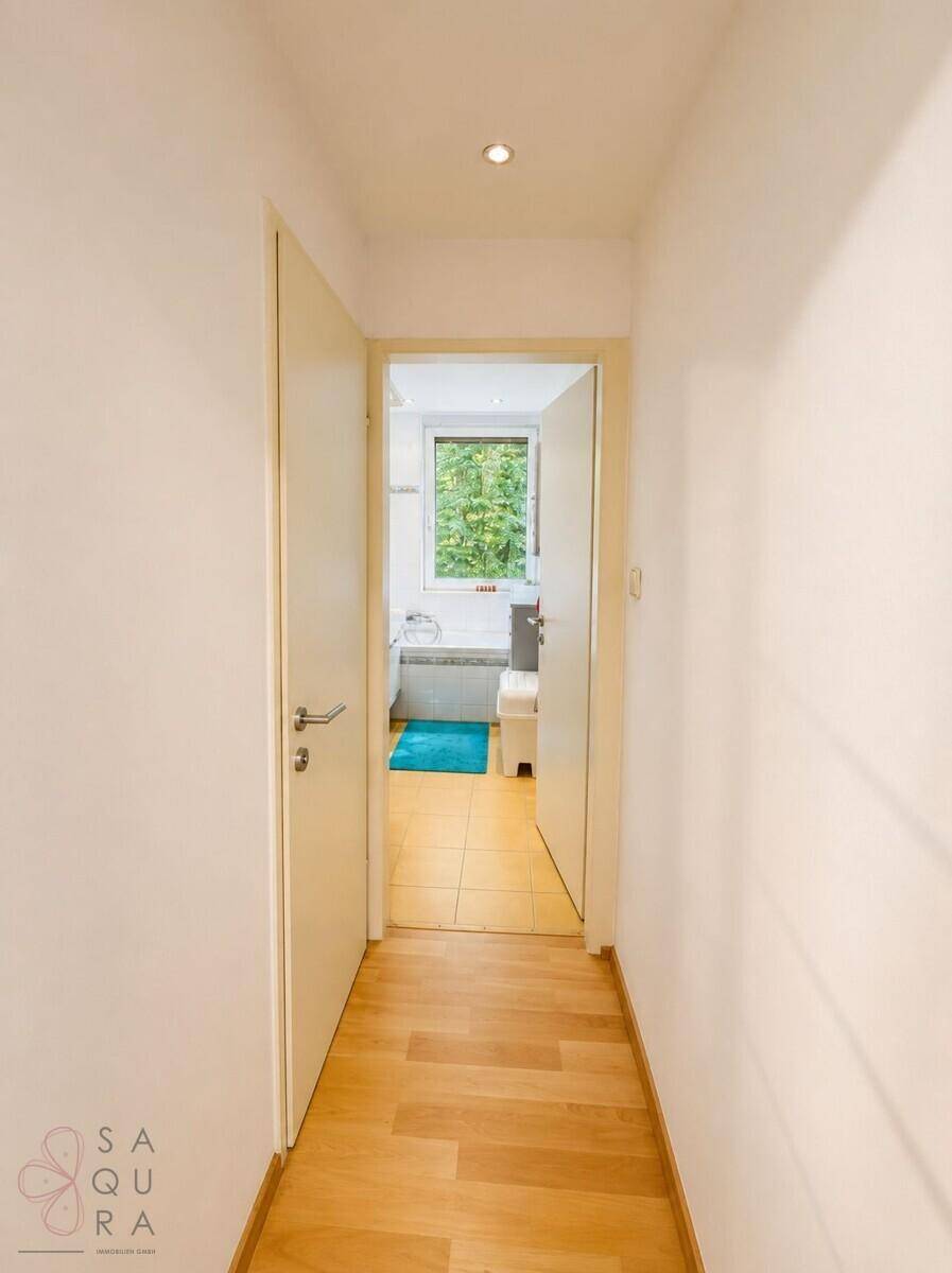 Heller Flur mit Holzfußboden, der zum Badezimmer führt.