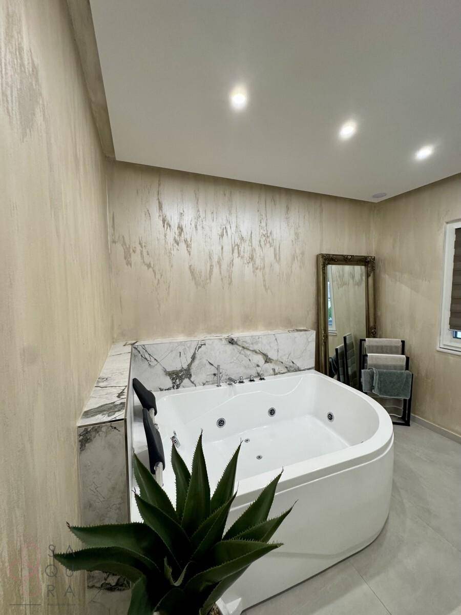Modernes Badezimmer mit großem Eck-Whirlpool, Marmor-Akzenten und beigen Wänden.