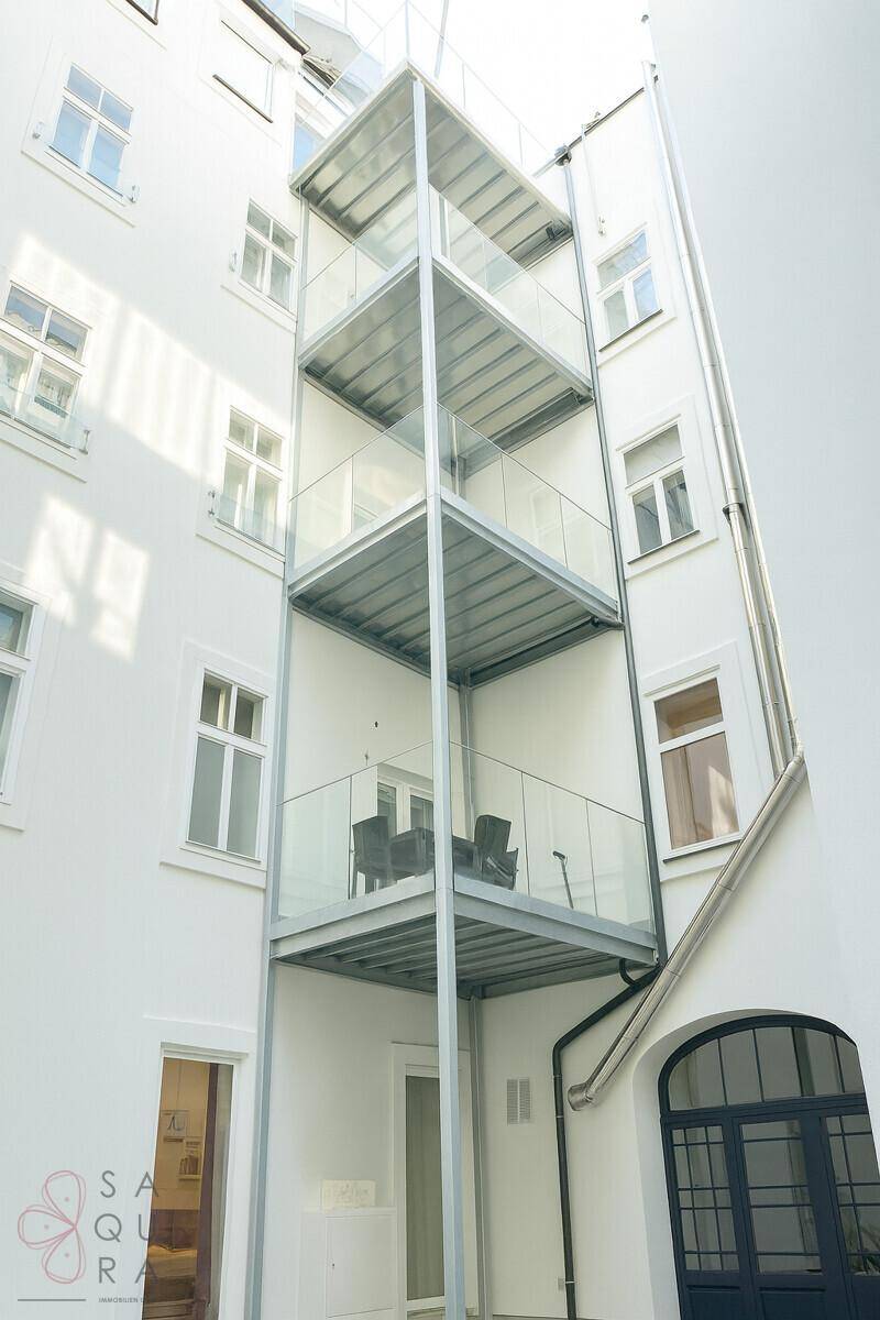 Mehrere Balkone an der Gebäudefassade, mit Glasgeländern und Metallkonstruktion.