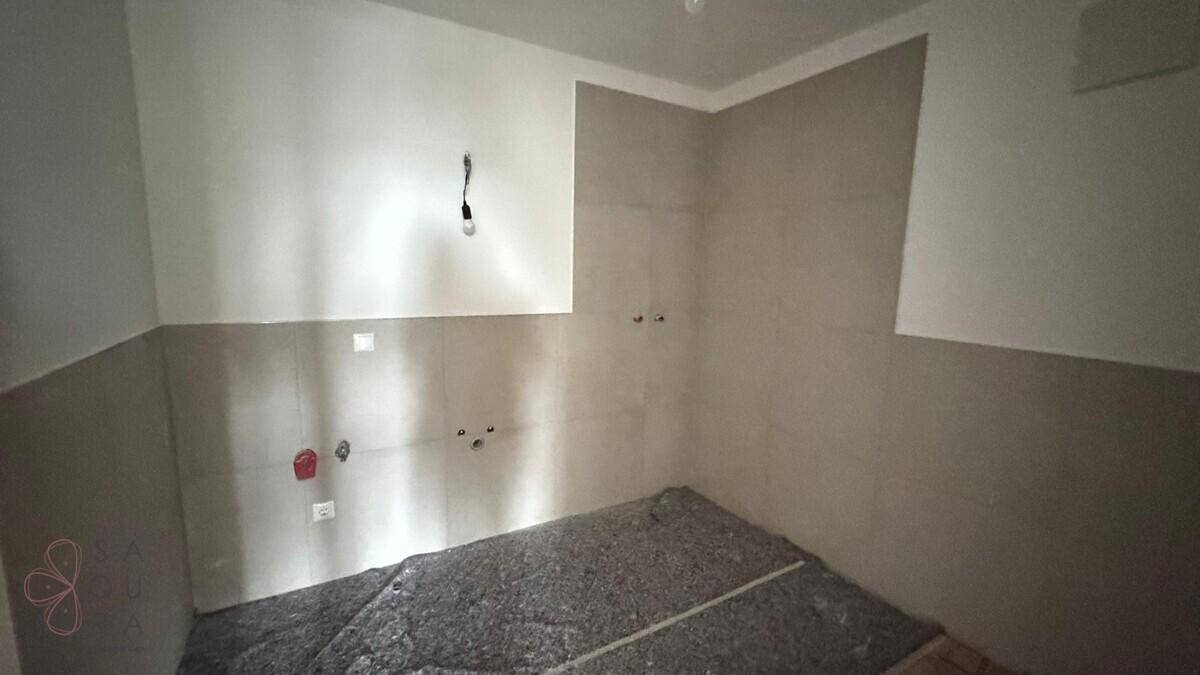 Helles Badezimmer im Rohbau mit gefliesten Wänden und vorbereiteten Wasseranschlüssen.