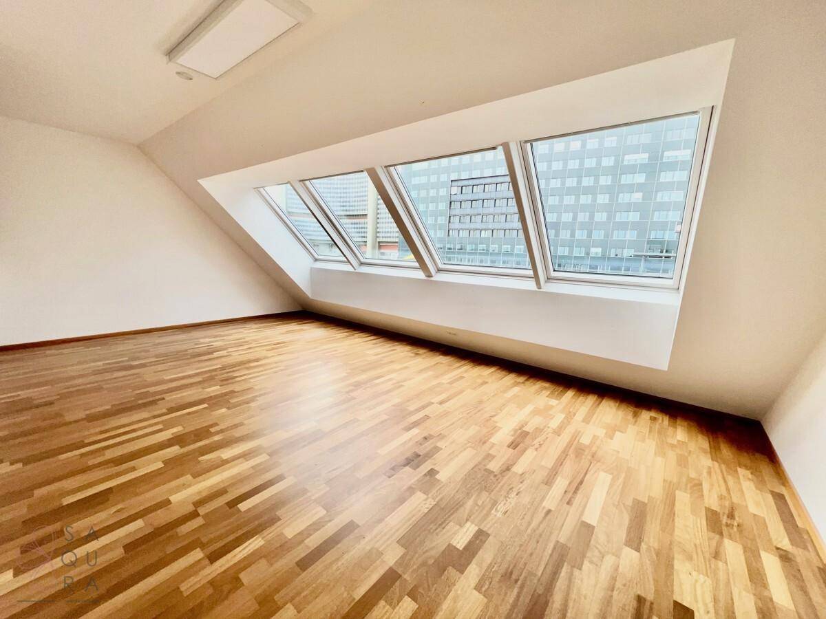 Helles Schlafzimmer mit Holzboden, Dachschrägen und großen Dachfenstern, die viel Tageslicht spenden.