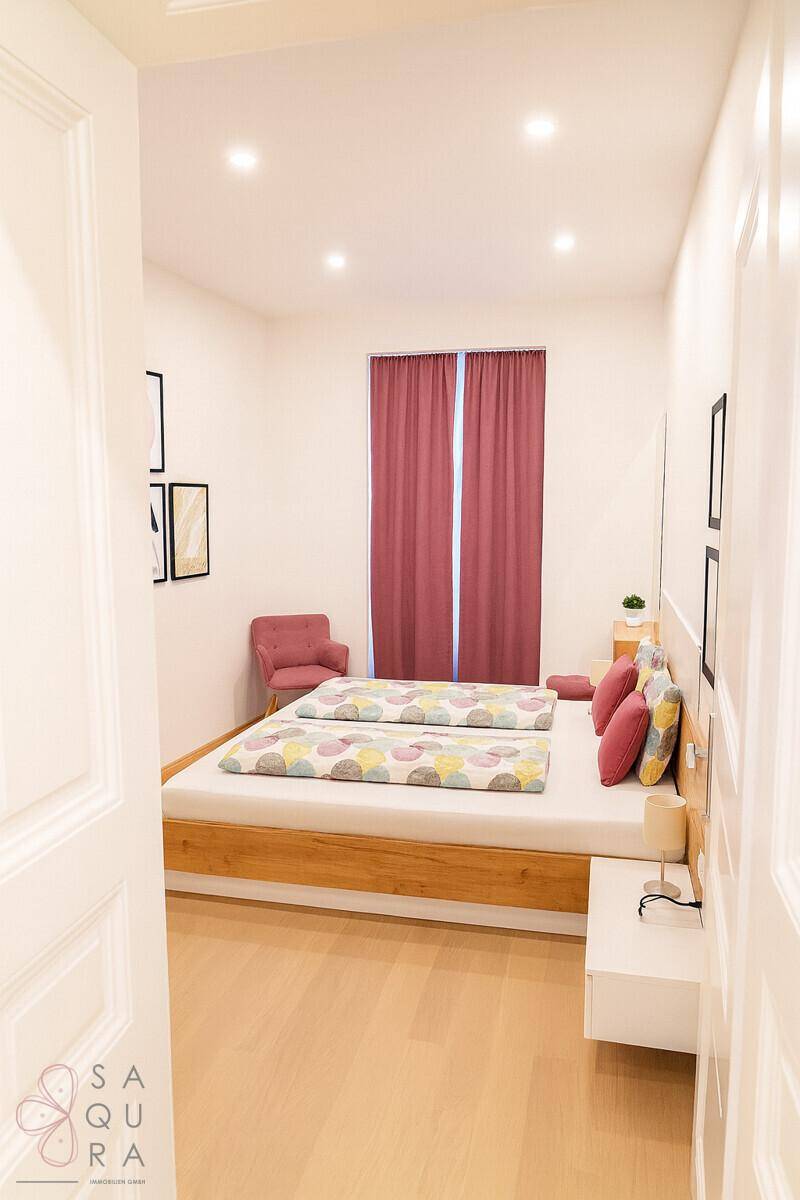 Gemütliches Schlafzimmer mit Doppelbett, Holzrahmen und roten Vorhängen, hell und einladend.