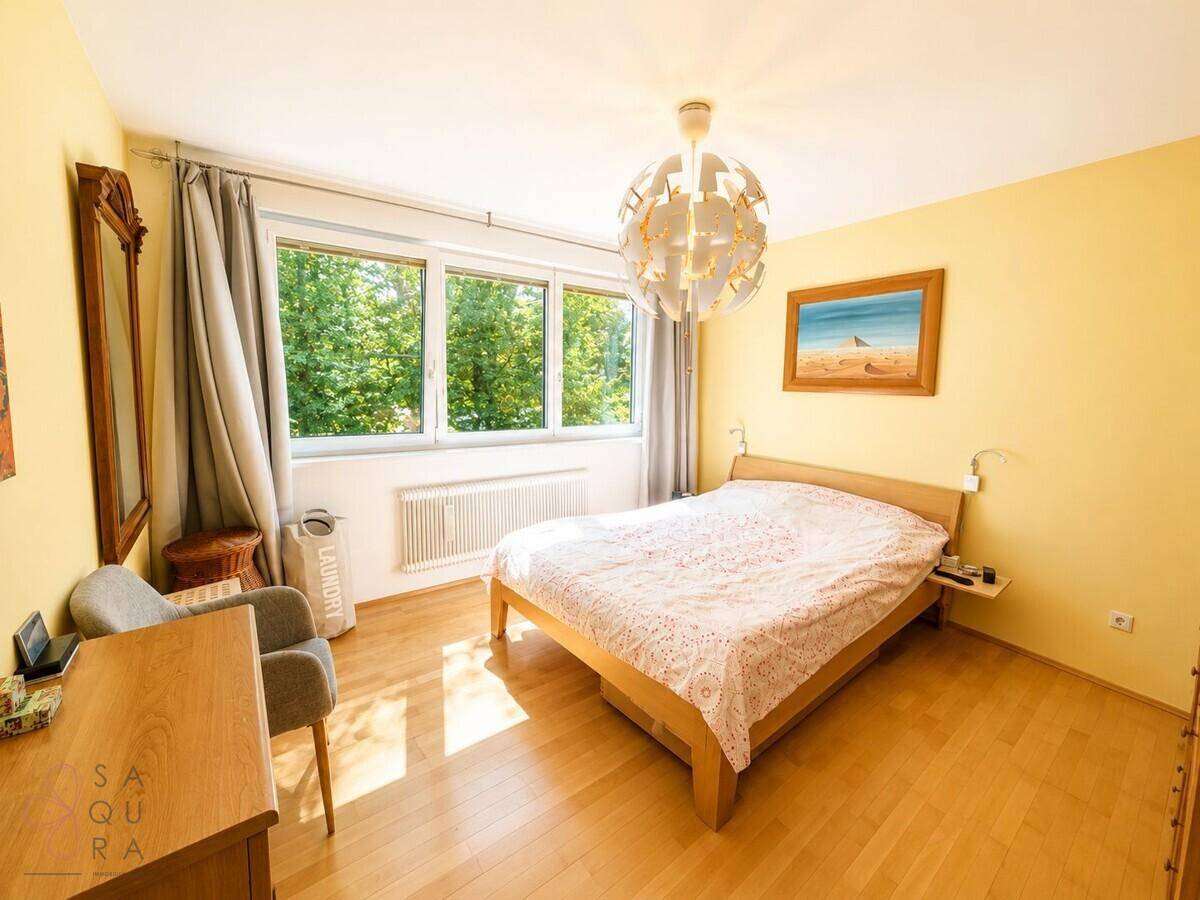 Gemütliches Schlafzimmer mit Doppelbett, Holzfußboden und Blick ins Grüne.
