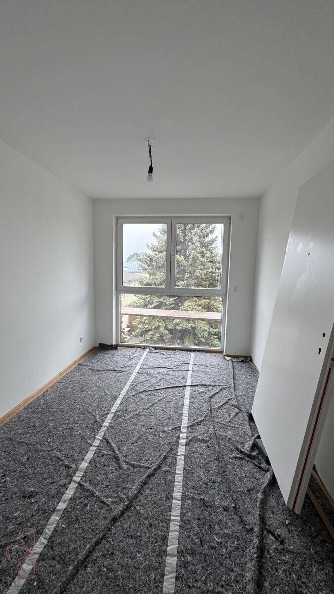Raum im Bauzustand mit Fenster und vorbereitetem Unterboden, bereit für den weiteren Ausbau.