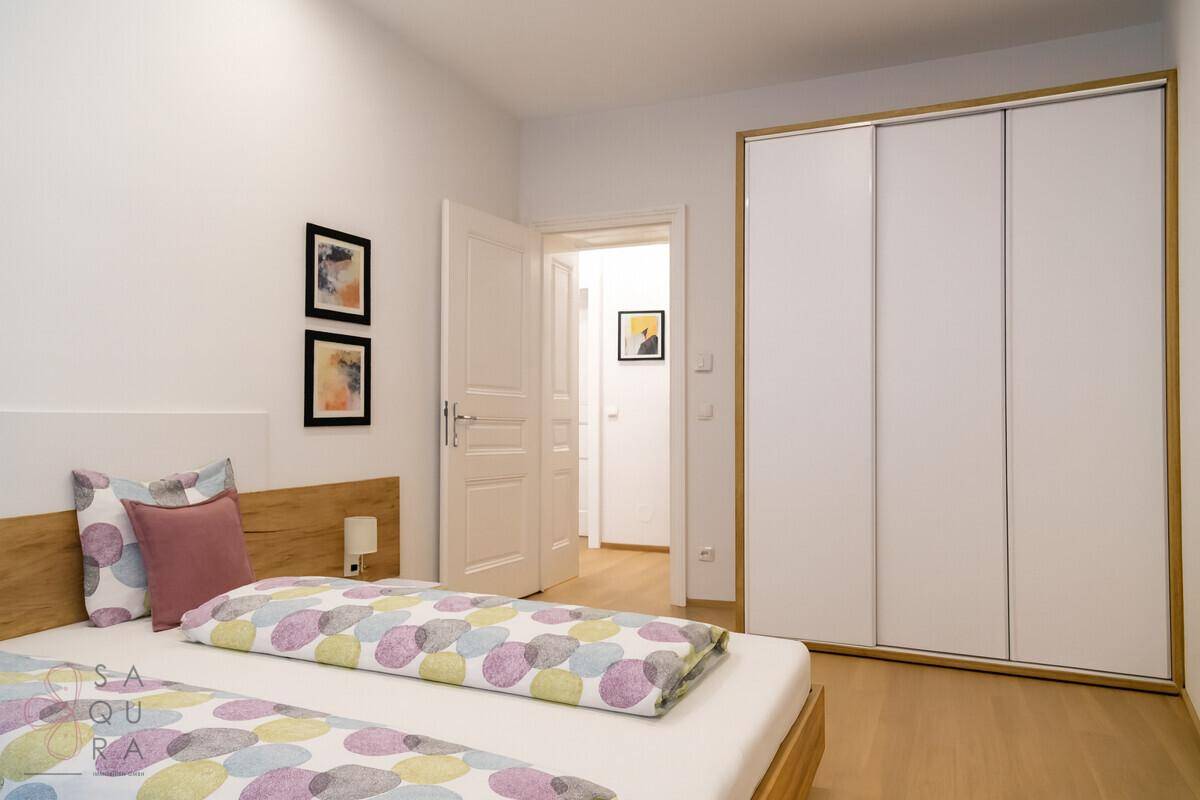 Schlafzimmer mit Doppelbett und großem Kleiderschrank, helle Wände und Parkettboden.