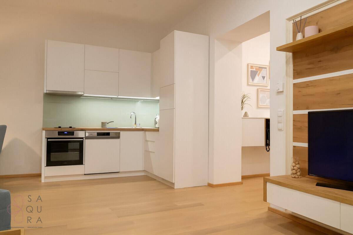Moderne Einbauküche mit weißen Schränken und integrierten Geräten, offen zum Wohnbereich.
