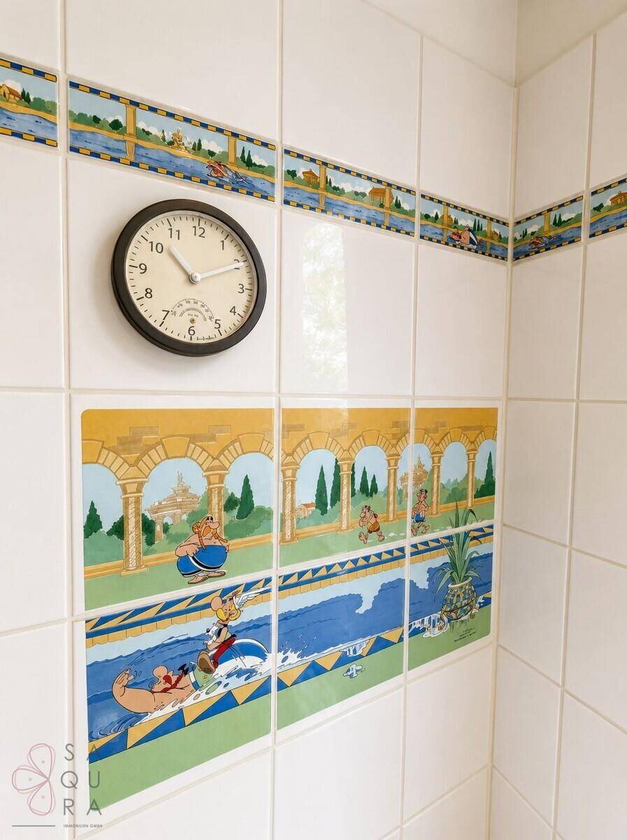 Badezimmerfliesen mit verspielten Comic-Motiven und einer Wanduhr, die eine persönliche Note verleihen.