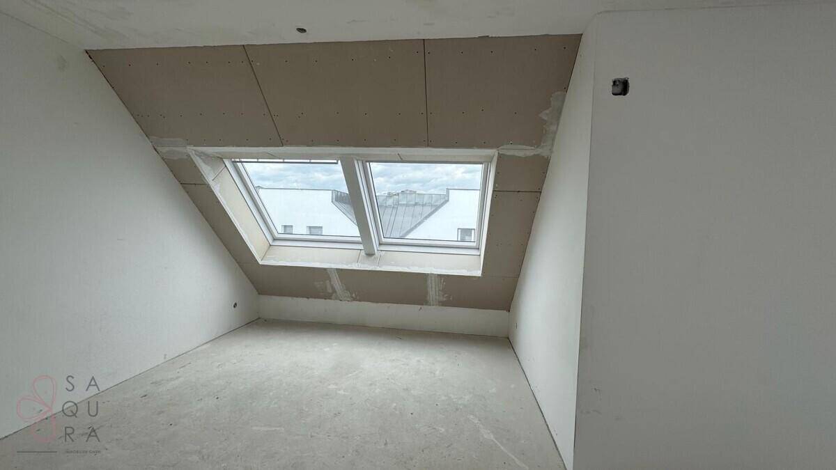 Dachgeschosszimmer im Rohbau mit zwei Dachfenstern, bereit für den Innenausbau und Gestaltung.