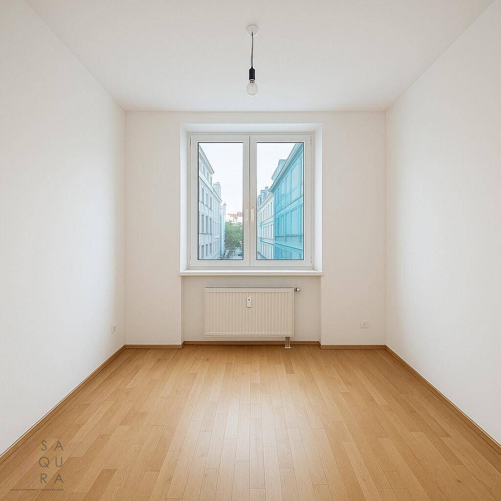Leerer Raum mit Laminatboden und Fenster mit Blick auf die umliegenden Gebäude.