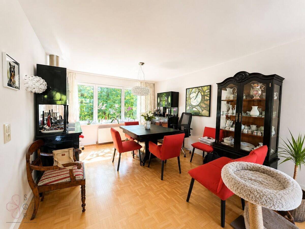 Eleganter Essbereich mit schwarzem Tisch, roten Stühlen und klassischer Vitrine.