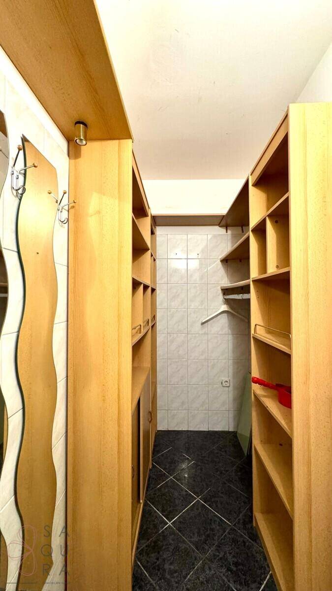 Leere Speisekammer mit Holzregalen und Fliesenboden, bereit zur individuellen Nutzung.