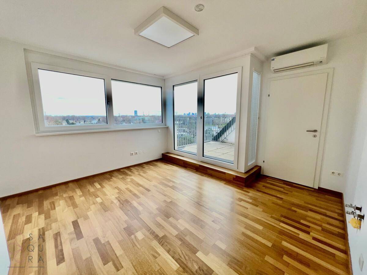 Helles Schlafzimmer mit Holzboden, Klimaanlage und Zugang zu einer Terrasse, die einen weiten Blick bietet.
