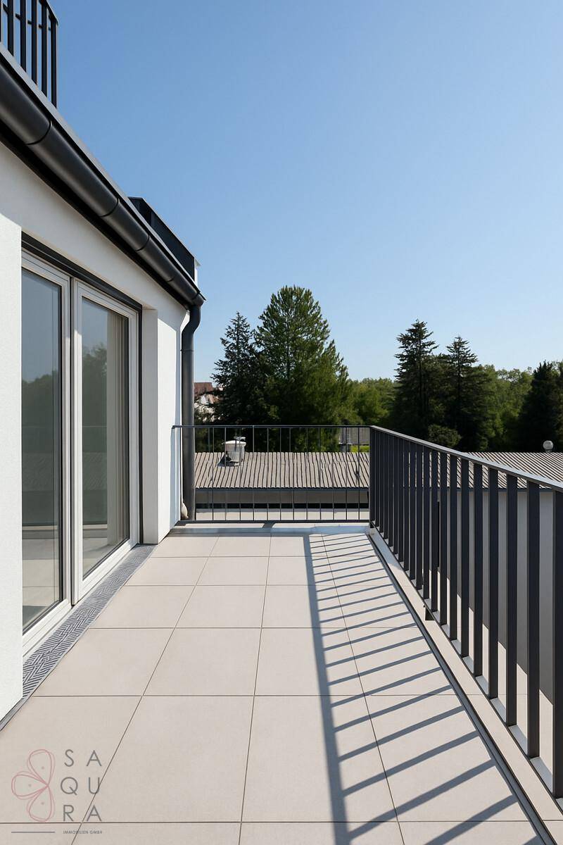 Heller Balkon mit Fliesenboden und modernem Geländer, bietet einen Blick ins Grüne.