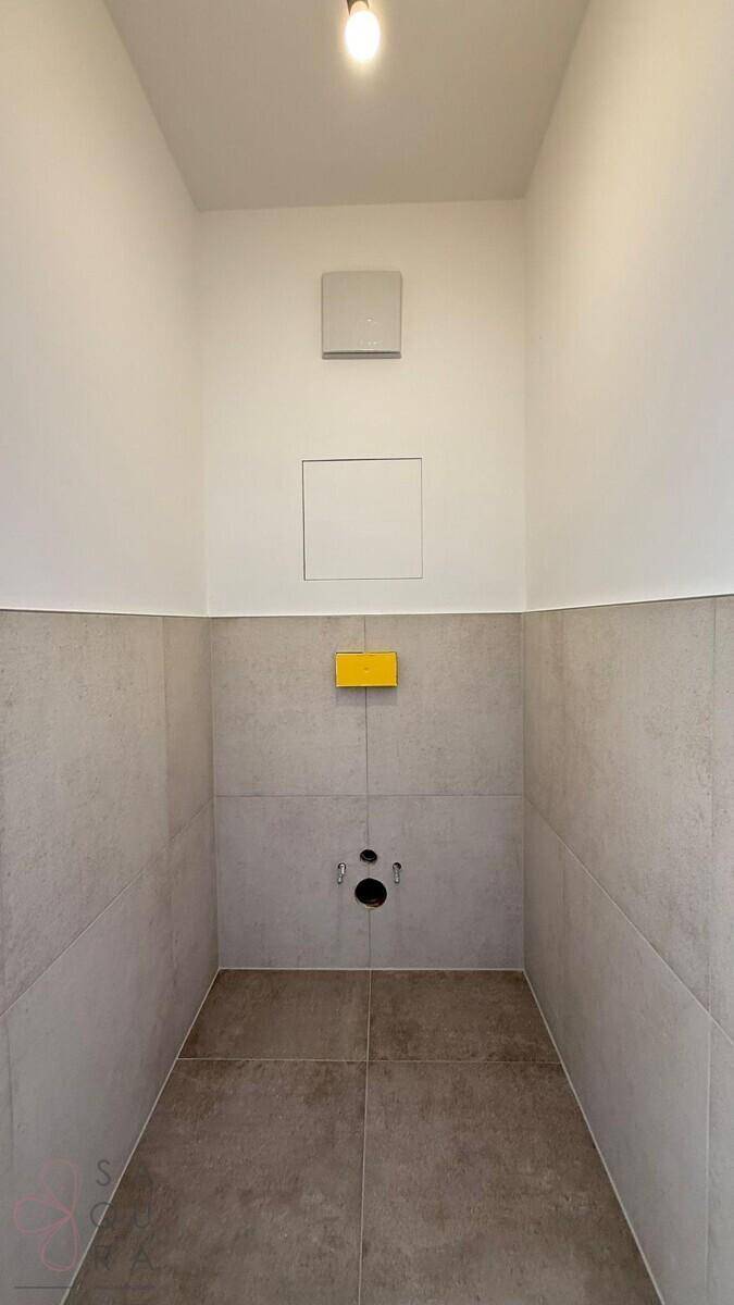 Unfertiges Gäste-WC mit grauen Fliesen, bereit für die Installation der Sanitärobjekte.