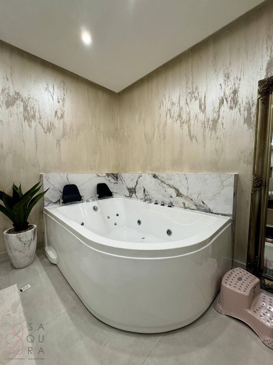 Geräumiges Badezimmer mit luxuriösem Eck-Whirlpool und eleganten Marmoroberflächen.