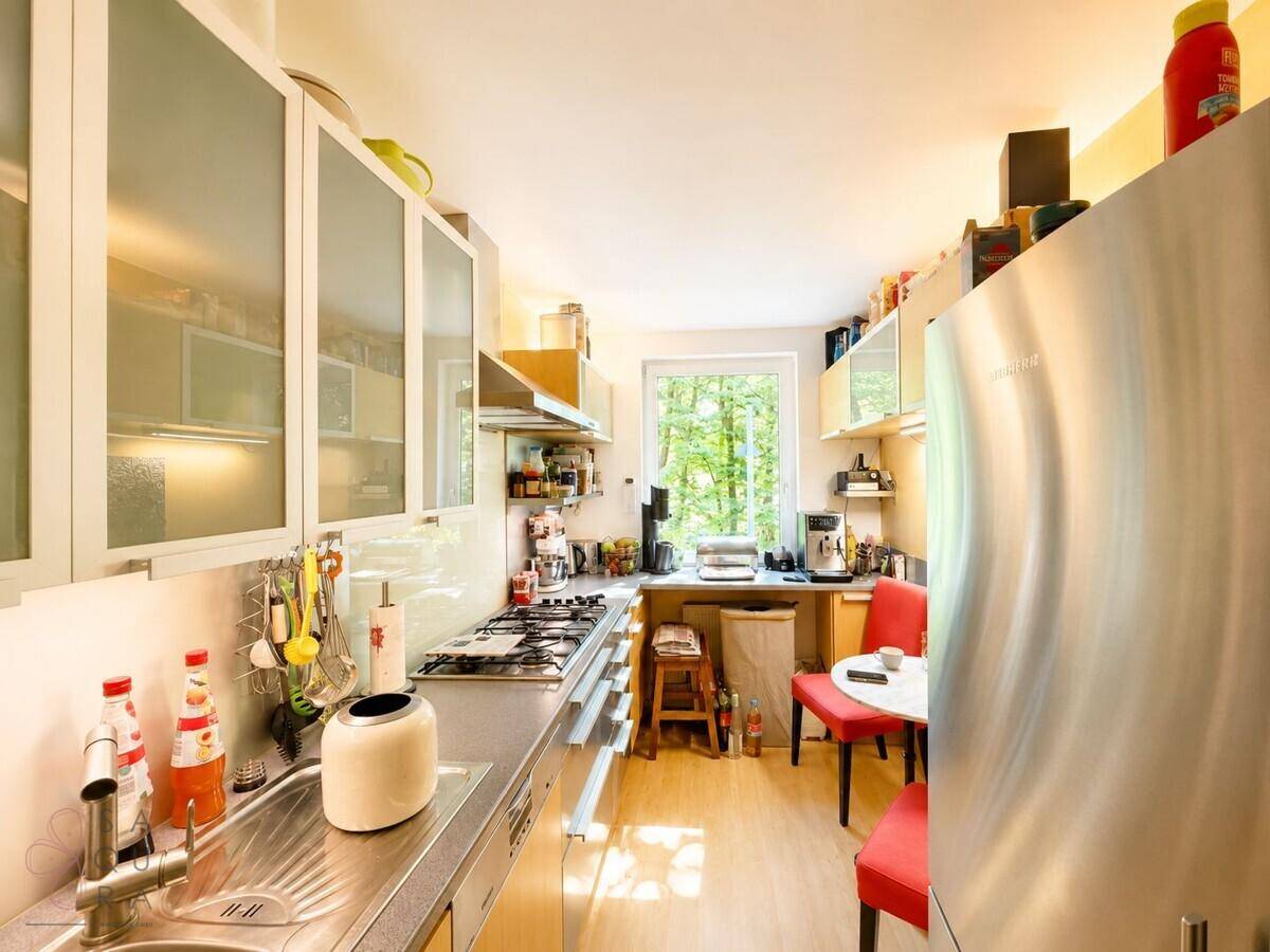 Funktionale Küche mit Gasherd, Edelstahlspüle und großem Kühlschrank.